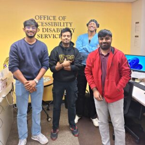 This is a photo of four student workers at the SDS standing in front of the Office of Accessibility and Disability Services sign.